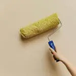 Hometown Paint teams painting a soft yellow wall in home exterior