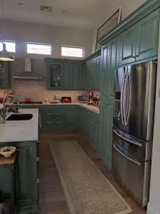 Refinished green kitchen cabinets with white countertops and stainless steel refrigerator in Phoenix, AZ
