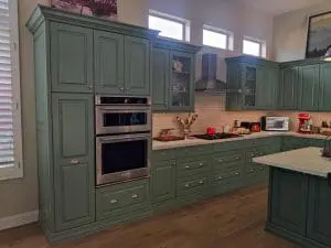 Refinished green kitchen cabinets with stainless appliances and white tile backsplash in Scottsdale, AZ