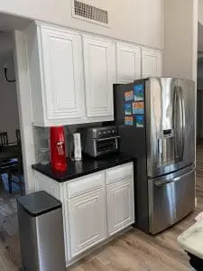 Refinished white kitchen cabinets with black countertops and stainless appliances in Phoenix, AZ