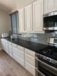 Close-up of refinished white kitchen cabinets with black countertops and stainless steel stove