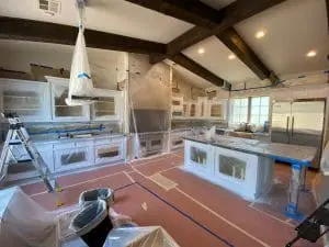 Kitchen fully prepped for cabinet painting with taped surfaces and protective plastic coverings
