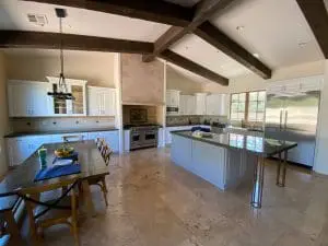Spacious kitchen with white cabinets, exposed ceiling beams, and large central island