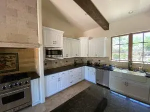 Luxury kitchen with white painted cabinets, black countertops, and natural light