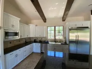 Bright kitchen with white refinished cabinets, farmhouse sink, and stainless steel appliances