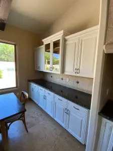Refinished white kitchen cabinets with dark granite countertops and tile backsplash in Arizona home
