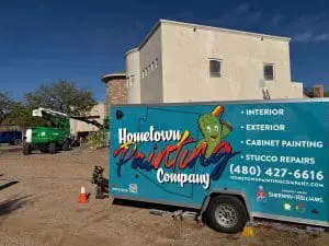 Hometown Painting Company trailer and crew painting Scottsdale home exterior with lift equipment