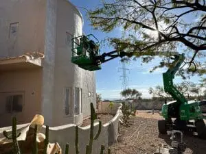 Hometown Painting team using lift to prep and paint tall stucco home exterior in Scottsdale, AZ