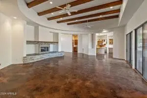 Freshly painted open living room with wood ceiling beams and stone fireplace in Scottsdale, AZ